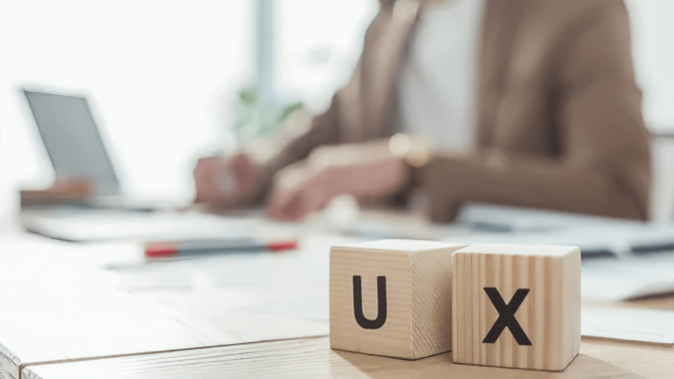 Un bureau de travail avec en premier plan deux cube de bois écrit "UX"