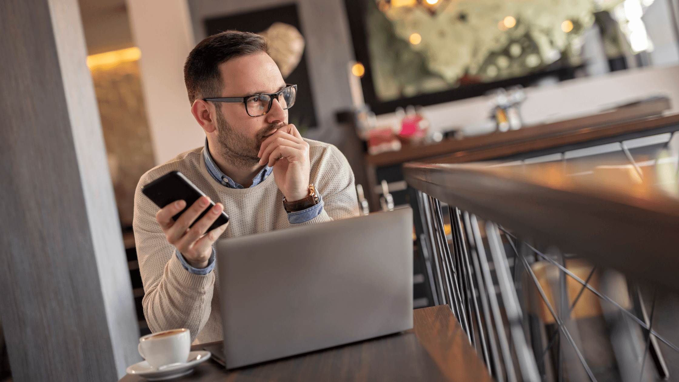 Un homme dans un café avec son PC et son portable à la main